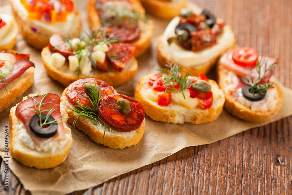 Crostini with different toppings on wooden background. Delicious appetizers. Front view. Crostini with different toppings on wooden background. Delicious appetizers. Front view.