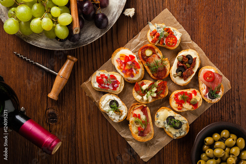 Crostini with different toppings on wooden background. Delicious appetizers. Top view.