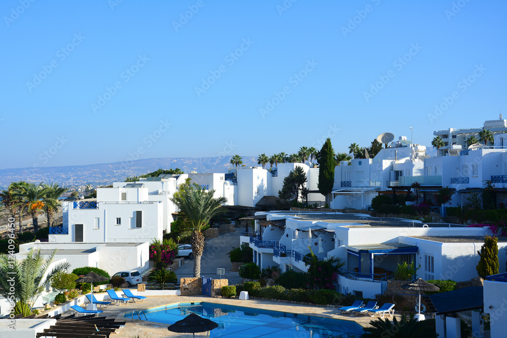Classical Greek architectureat dawn: white and blue dotted buildings, palm trees, swimming pool