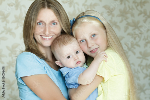 Family of three smiling and hugging people indoor portrait