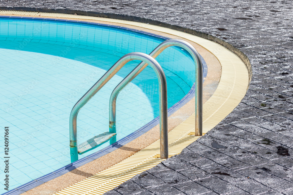 A view of a light clear blue swimming pool with steel ladder.
