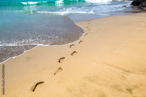 footprints in the sand, leading to the sea