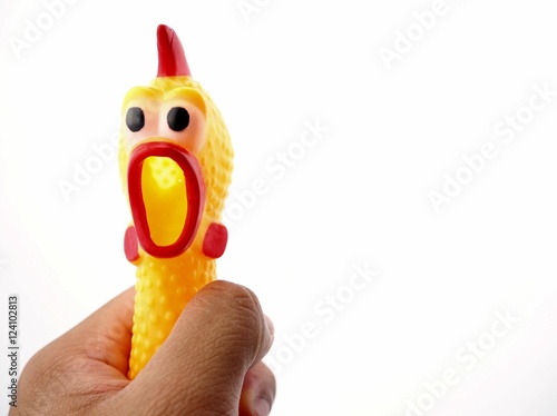 Hand squeezing the neck of yellow shrilling chicken with red lips