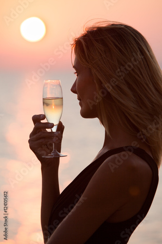 femme buvant du champagne au coucher du soleil
