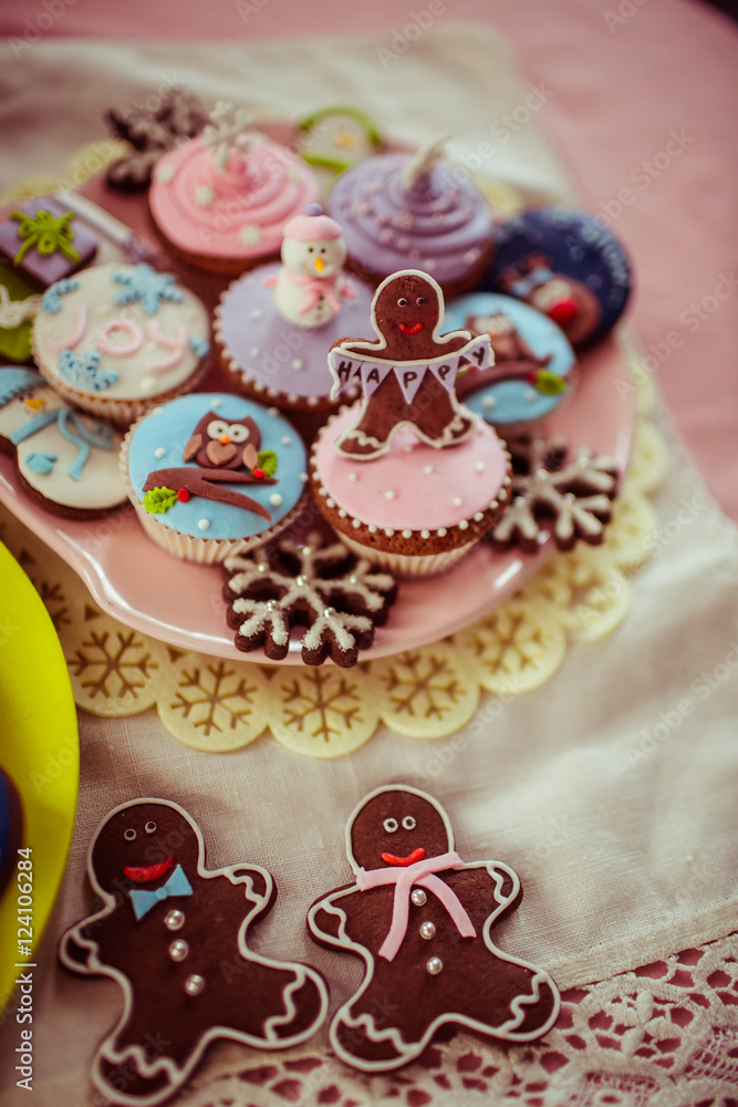 Gingerbreads and cupcakes lie on the colorful plate decorated wi