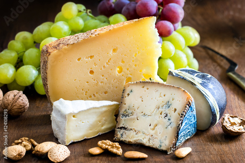 Appetizing cheese variety with nuts and grapes.