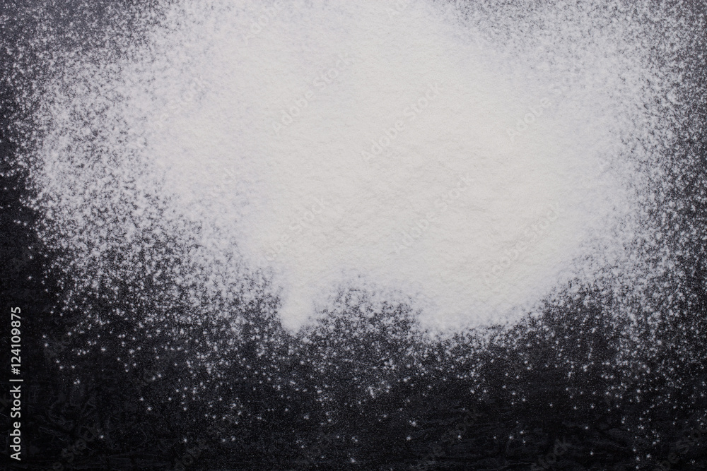 Flour spilling on black metal background