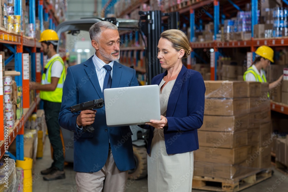 Warehouse manager and client using laptop Warehouse manager and client using laptop
