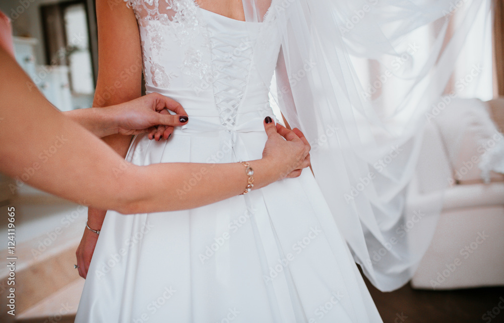 Woman with black nails adjusts a bow on bride's dress Woman with black nails adjusts a bow on bride's dress