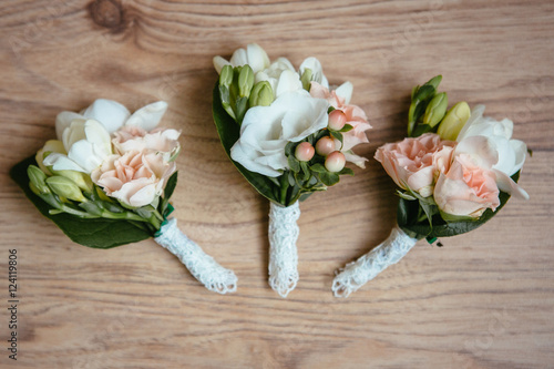 Tender pink and white boutonniere lie on the wooden table