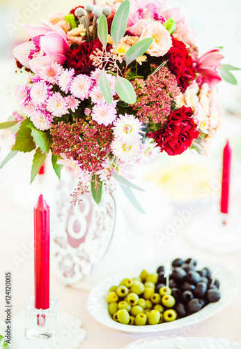 Olives on white plate stand under the bouquet