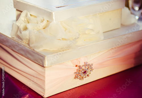 Present boxes covered with beig cloth and crystals stand on the