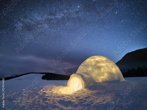 Winter night landscape with a snow igloo and a starry sky