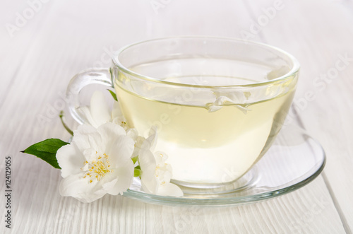 Glass cup of tea with jasmine on the white wooden background