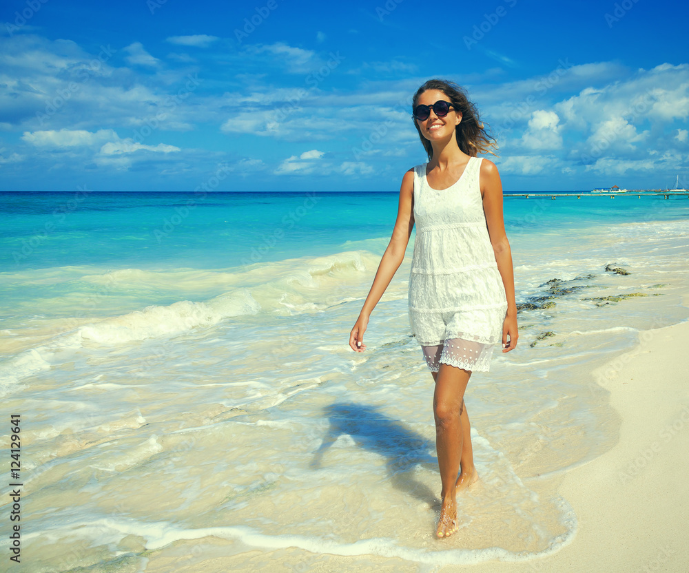 Young woman walking along white sand tropical beach. Beautiful girl in white dress on the beach. Travel and vacation. Freedom concept. Young woman walking along white sand tropical beach. Beautiful girl in white dress on the beach. Travel and vacation. Freedom concept.