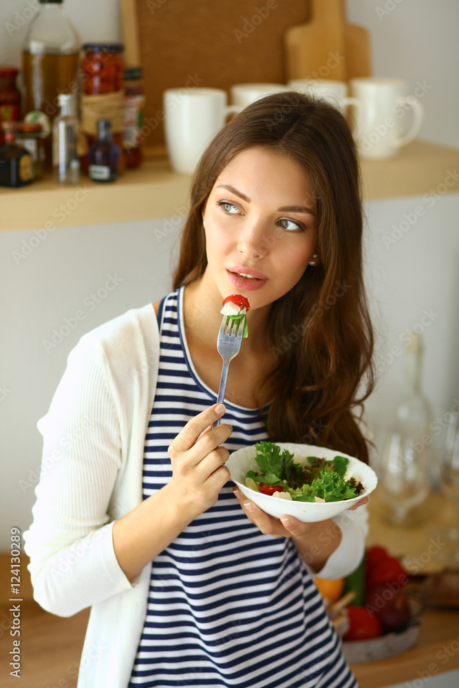 Young woman eating salad and holding a mixed salad Young woman eating salad and holding a mixed salad