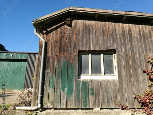 Alter Schuppen mit braunem Bretterverschlag auf einem Bauernhof bei blauem Himmel und Sonnenschein in Asemissen bei Leopoldshöhe und Bielefeld am Teutoburger Wald in Ostwestfalen-Lippe photo