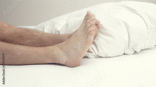 closeup of hairy legs and feet of man in bed