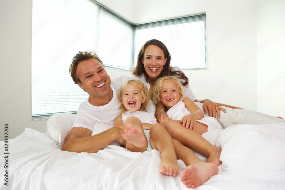 Cheerful family of four lying in bed at home