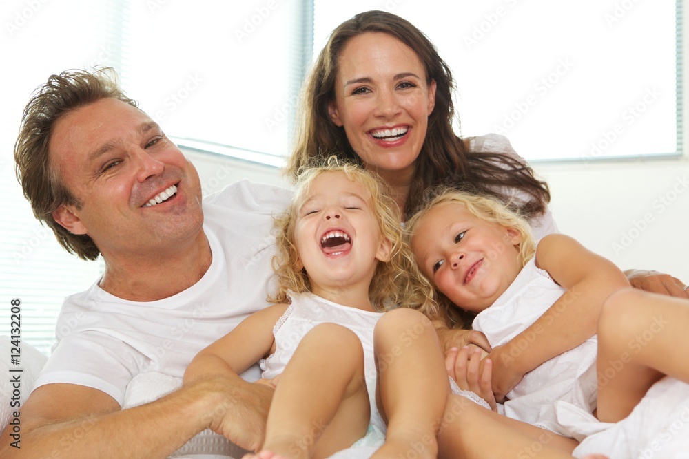 Happy young family of four in bed at home