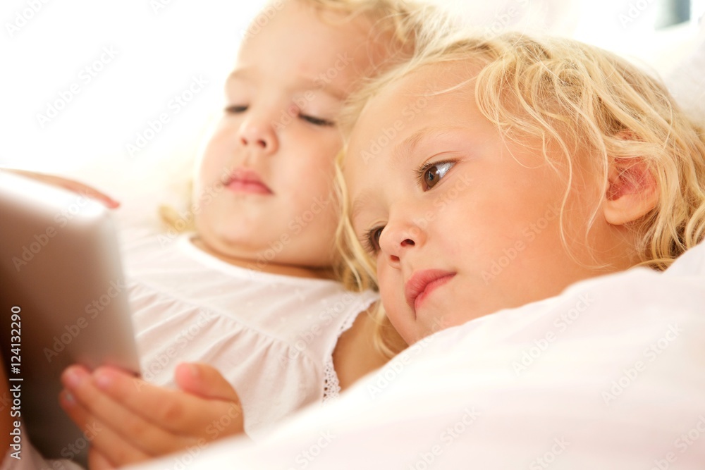 Two little sisters using digital tablet Two little sisters using digital tablet