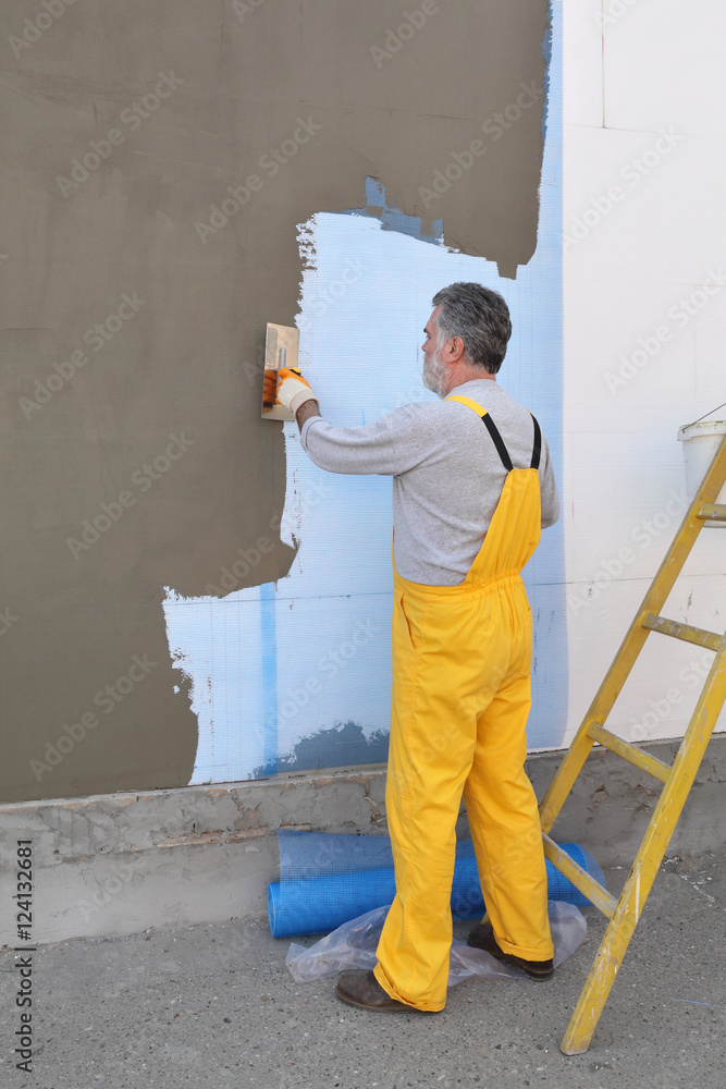 House renovation, polystyrene wall insulation, worker spreading mortar, use trowel