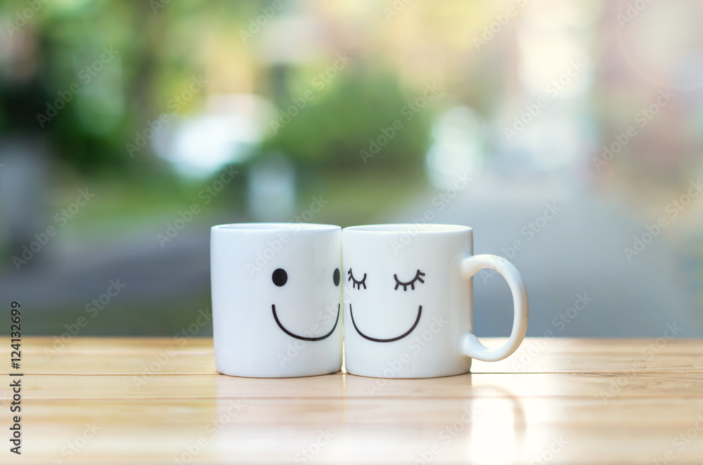 Two happy cups on wood table with bokeh, about love concept Two happy cups on wood table with bokeh, about love concept