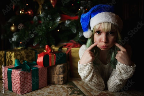 Portrait of sexy young girl under Christmas tree with presents