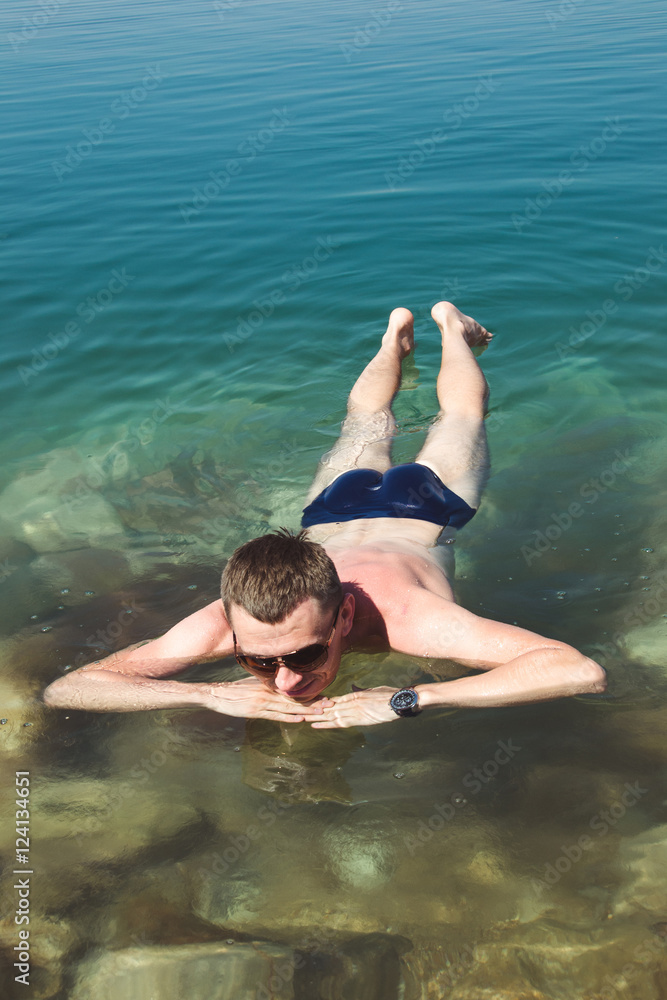 Man relaxing on water surface Dead Sea. Tourism recreation, healthy lifestyle concept. Peaceful meditation