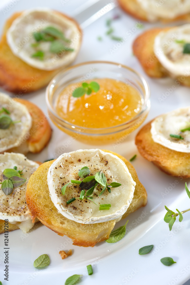 Gebackene Crostini-Partyhäppchen mit Ziegenkäse, frischen Kräutern und Feigenhonig serviert - Baked spicy crostini appetizers with goat cheese and fresh herbs served with fig honey