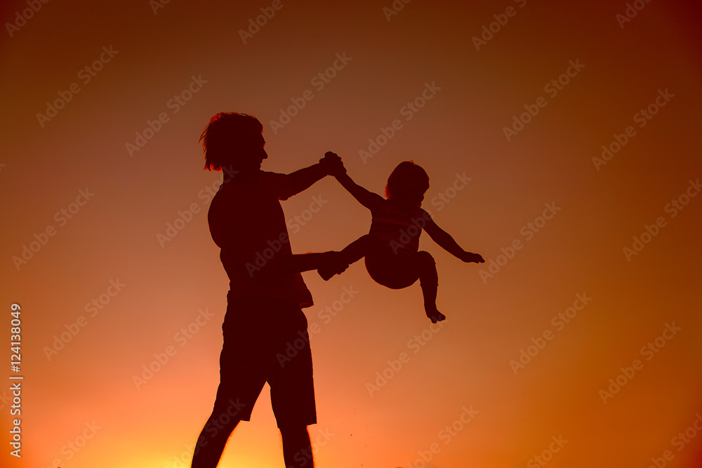 Father and little daughter silhouettes play at sunset
