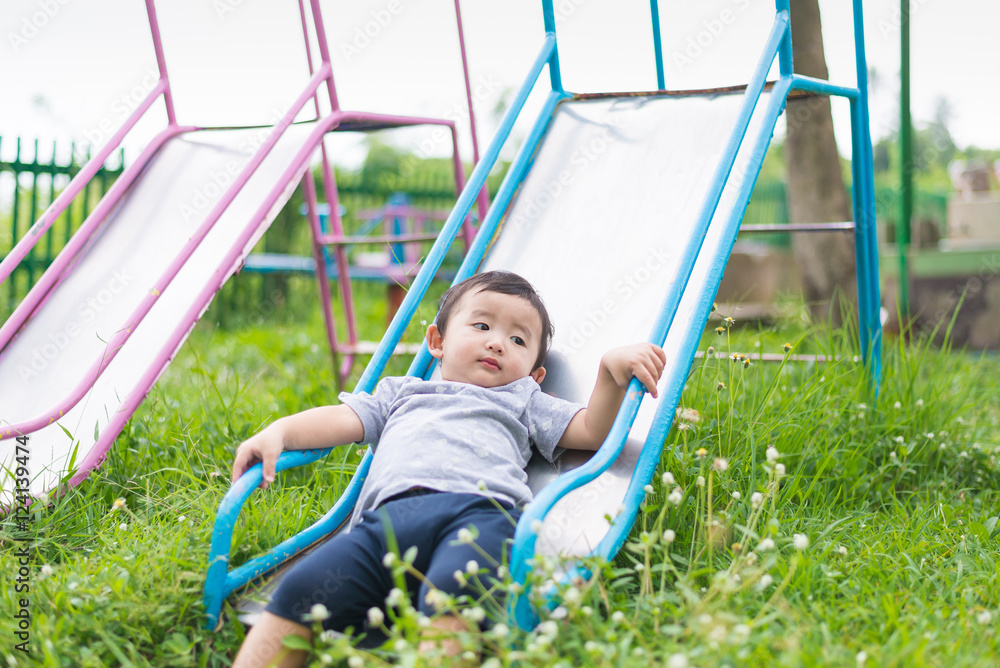 Little Asian kid playing slide at the playground Little Asian kid playing slide at the playground