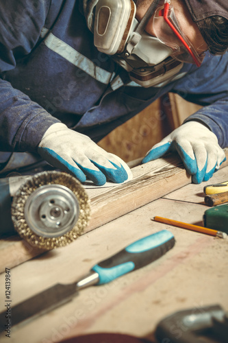 Man carpenter polishing wooden bar in his home workshop