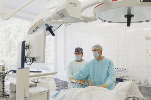Surgeons team preforming operation in hospital operating theater, Surgeon operating patient,wearing surgical gown,operating room, holding hands,working with surgical instruments. Laparoscopy