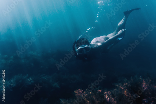 Female free diver swimming among seaweed