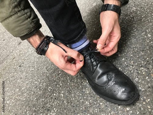 Man tying shoelaces shoes in the street
