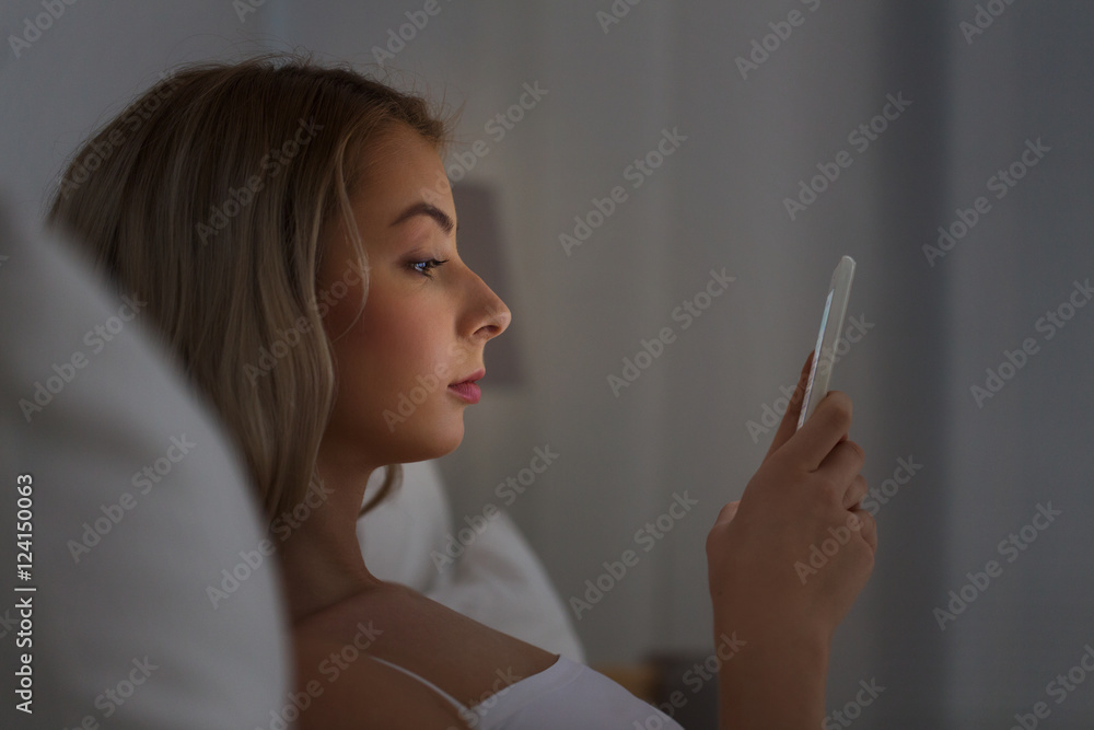 young woman with smartphone in bed at night young woman with smartphone in bed at night