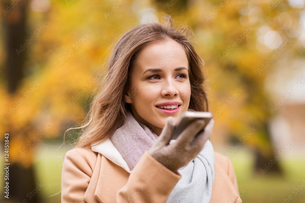 woman recording voice on smartphone in autumn park woman recording voice on smartphone in autumn park