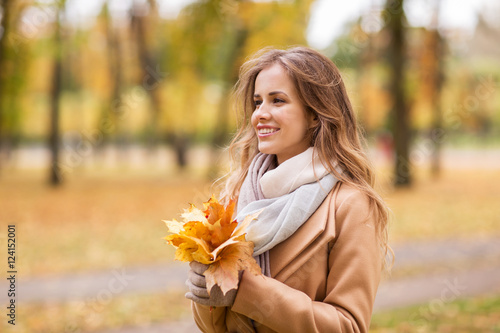 beautiful woman with maple leaves in autumn park
