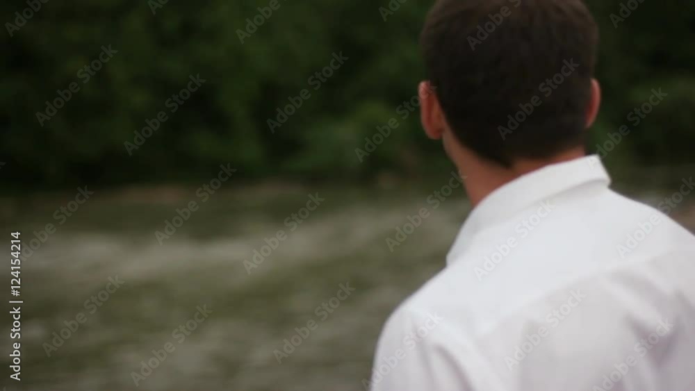 Happy stylish groom standing near the river Happy stylish groom standing near the river