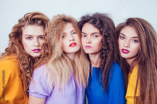 Fashion girls in bright clothes. Beautiful women with professional makeup and crazy hair style, over white background.