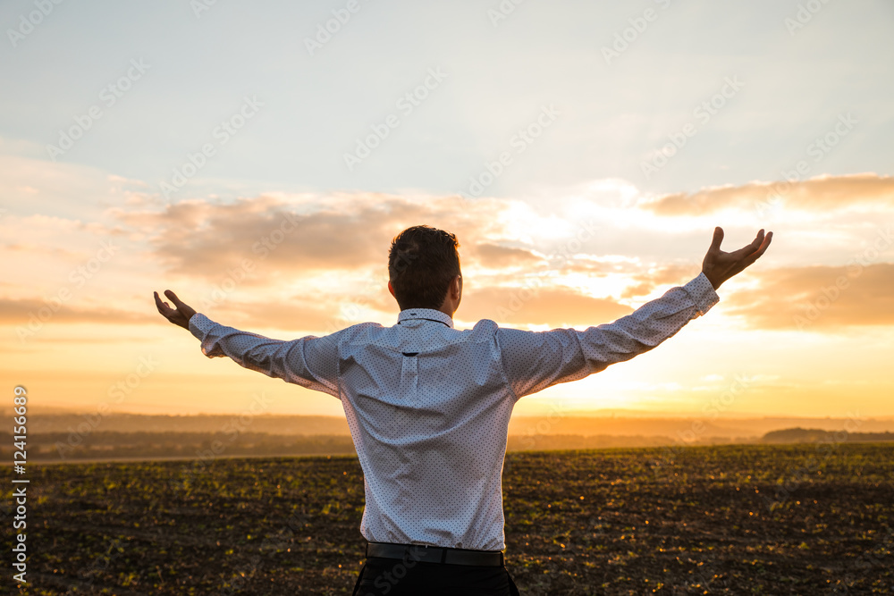 Thankful Businessman with Open Arms at the Field on sunset. Back side photo Thankful Businessman with Open Arms at the Field on sunset. Back side photo
