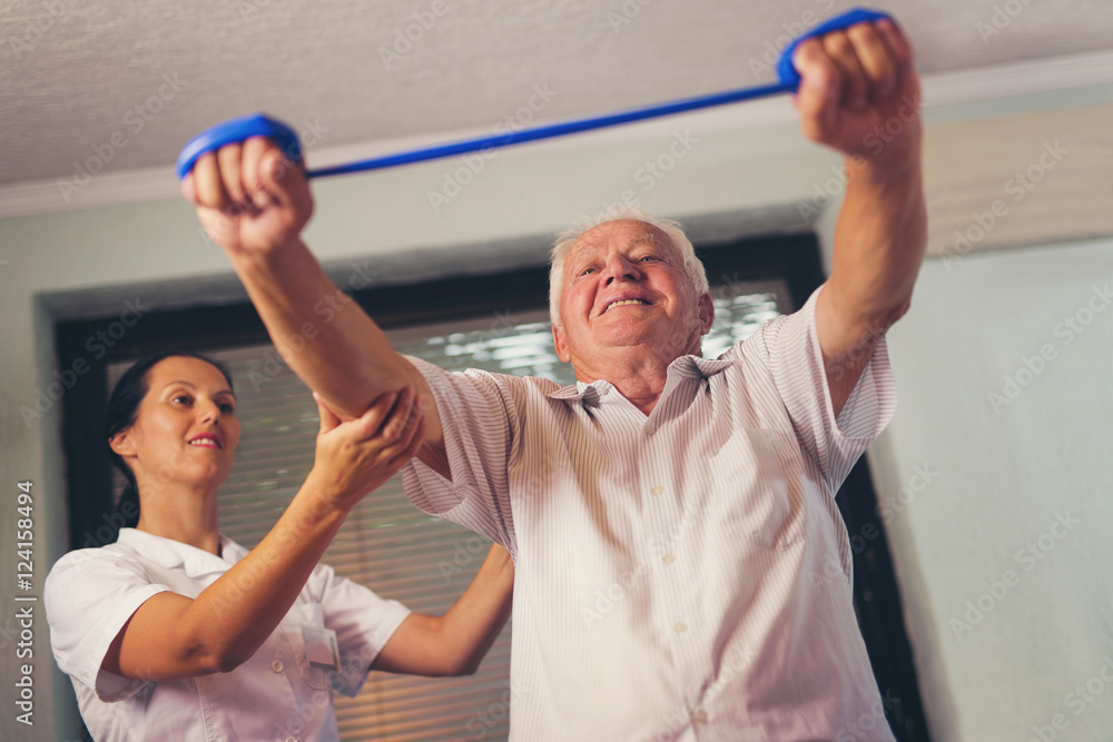 Senior man doing exercises using a strap to extend and strenthen - obrazy, fototapety, plakaty 