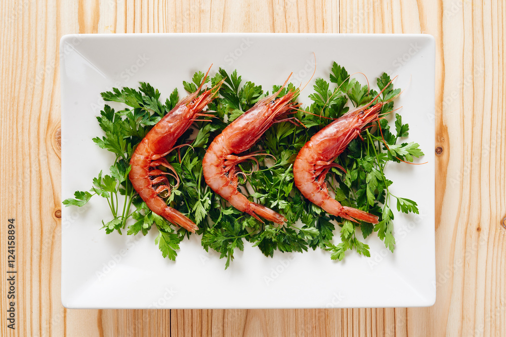 Raw prawns and parsley on white dish Raw prawns and parsley on white dish