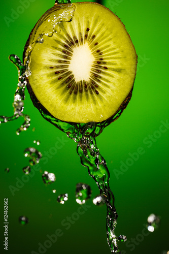 Kiwi in water splash, isolated on green background