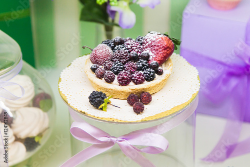 Fresh berry tarts filled with custard, raspberry, blueberry, powdered sugar and blackberry delicious dessert.