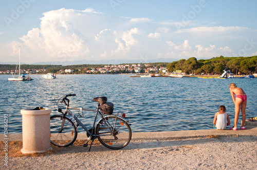 Two girls playing on a sea shore near a bicycle