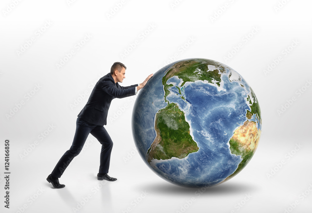 Side view of young businessman rolling the Earth isolated on white background Side view of young businessman rolling the Earth isolated on white background
