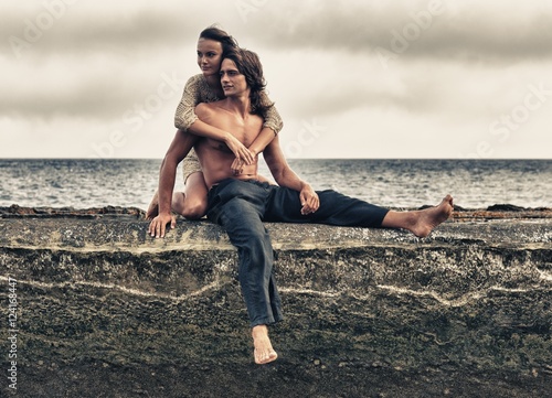 A Man And Woman Sitting On A Ledge Along The Ocean In Parque Natural Del Estrecho; Tarifa, Cadiz, Andalusia, Spain