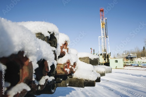 Edson, Alberta, Canada; Snow Covered Drilling Pipes With A Rig In The Background photo